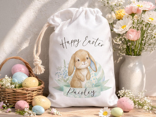 Personalised Easter bunny bag, with cute watercolor brown bunny design. Bunny has downturned floppy ears and a pale green banner across his feet featuring the name Paisley. A reusable Easter egg hunt drawstring sack.
