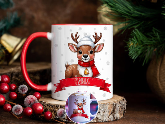 White Ceramic mug with a red rim and handle printed with a cute little Deer Fawn with a Cozy Bobble hat and Bright red scarf. A little gold bell hangs around his neck as snowflakes fall all around him. A Festive red Banner rests below him with the recipients name printed on. Personalised with any name and printed on both sides. Also available in plain white