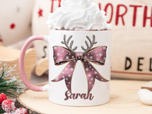 Load image into Gallery viewer, White Ceramic mug with a pink rim and handle printed with a Festive Pink &amp; Gold bow Topped with Glittery Reindeer Antlers with matching Name. Personalised with any name and printed on both sides. Bows also available in Green, Dark blue, Light Blue and Red
