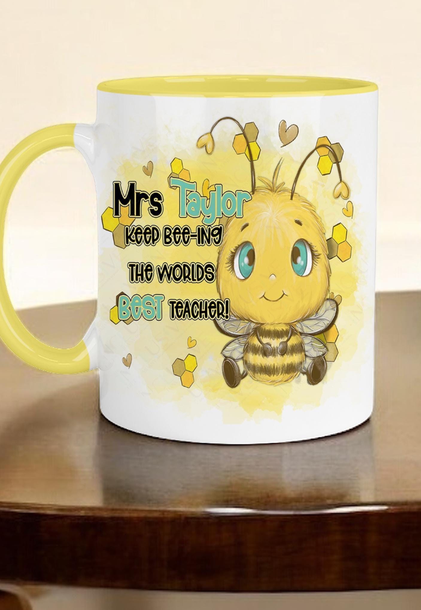 Glossy White Ceramic mug with a yellow handle and rim against a plain white background. A cute cartoon style bee with bright blue eyes is printed on each side of the mug with the words Teacher name Keep beeing the BEST Teacher in black and matching blue