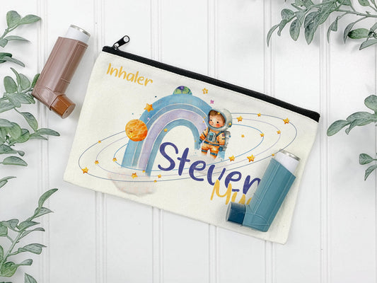 Offwhite canvas pouch for storing Asthma inhalers. Black zipper allows for secure closing. The design features a watercolor illustration of an astronaut, planets, stars, and a rainbow. Text includes "Inhaler"