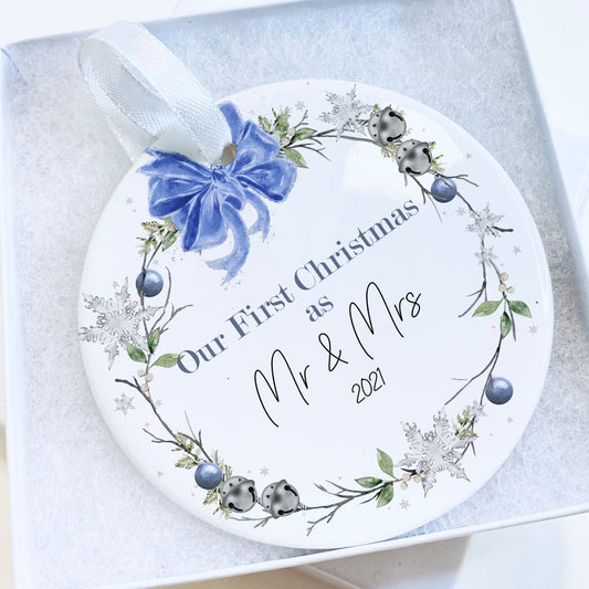Flat Ceramic white bauble printed with Blue and green floral wreath & sleigh bells topped with a blue bow design Message reads Our First Christmas as Mr & Mrs (year)