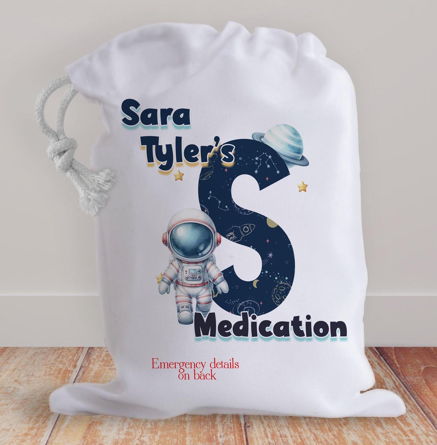 White drawstring bag. Printed with Initial of first name in a space theme with astronaut & text reading name's inhaler if you choose to have emergency contact on back it will state this is available on the front.