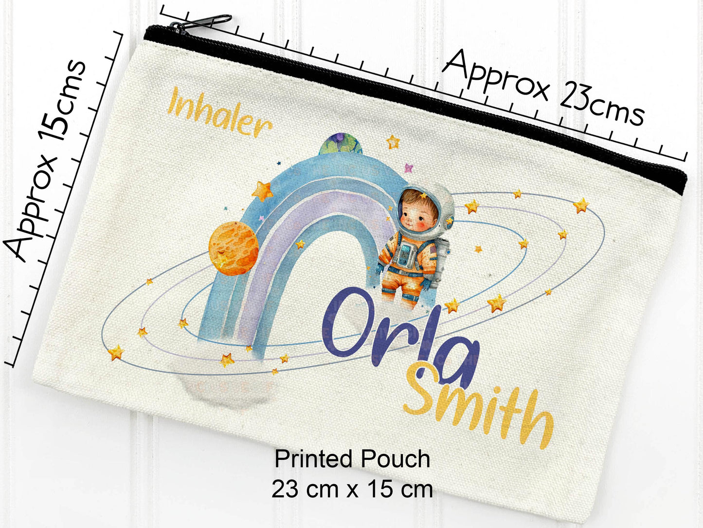 A rectangular canvas storage pouch with a black zip, measuring approximately 13 x 21 cm. The design features a watercolor illustration of an astronaut, planets, stars, and a rainbow. Text includes "Inhaler", "Orla Smith".