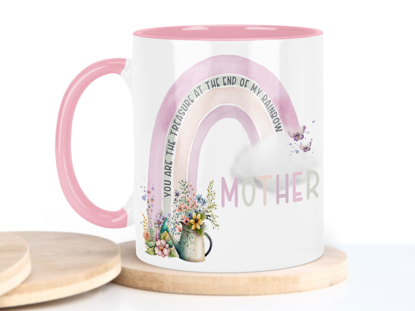 White ceramic mug with glossy Pink handle, rim and inner. Design shows A Pink and peach coloured rainbow with flowers and watering can at one end, cloud & butterflys at the other.