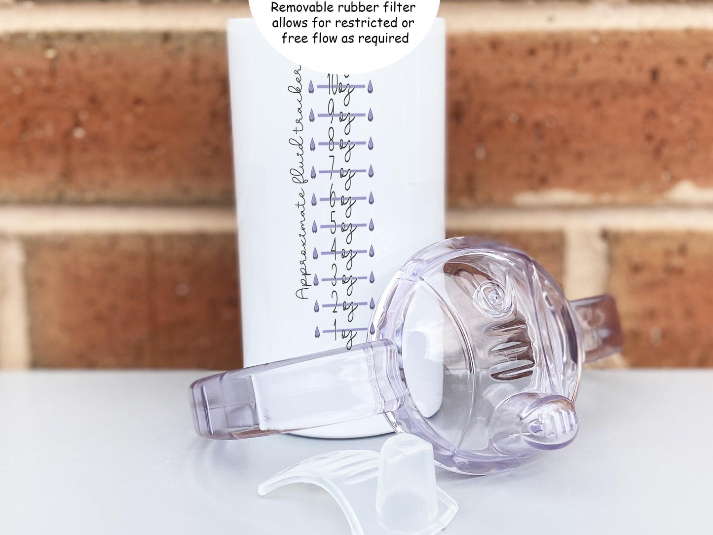 Close-up of 12 oz personalised adult sippy cup with clear handled lid and removable rubber flow filter shown separately, featuring an “Approximate Fluid Tracker” scale with purple water drop markers on the back.