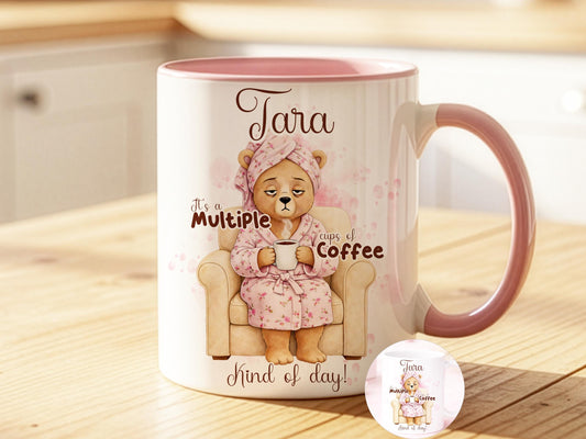 Personalised Coffee lover Mug With Name. White coffee mug with Light Pink Rim & Handle, also availble in an all white mug. Printed with a gorgeous sleepy bear relaxing in her arm chair with a white & Pink flowery bath robe and Head towel wrap holding a cup of strong coffee. Personalised with any name and the design text reads. Its a multiple cups of Coffee kind of day.