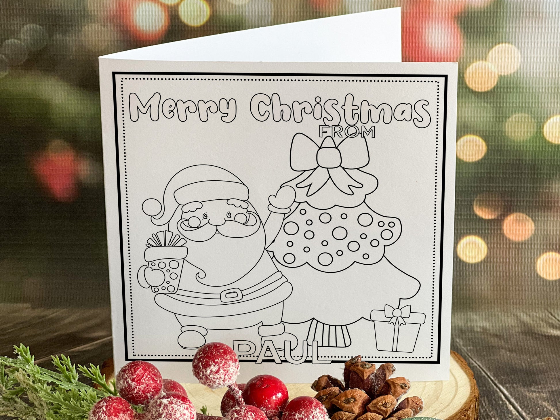 Colour your own White 5x5 inch sq card with black and white line drawing of Santa and Tree. Wordings reads Merry Christmas from Name)