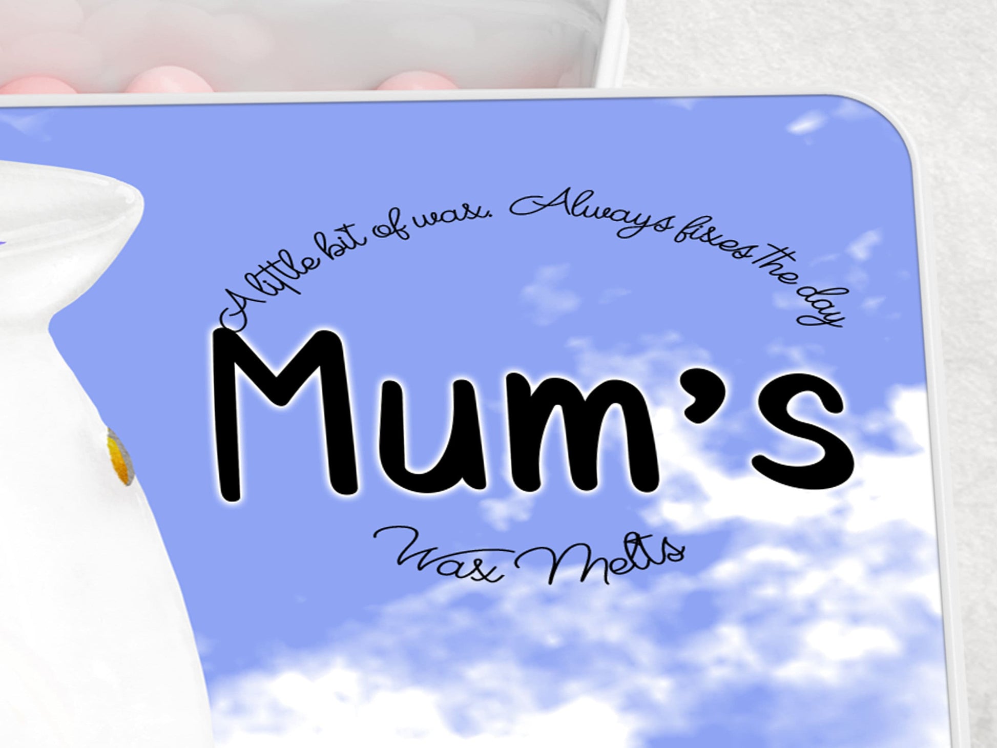 Close up of personalisation. Text is in black with the name in a chunky easy to read font A little but of wax always fixes the day and wax melts is written in a circle around the name in a cursive script