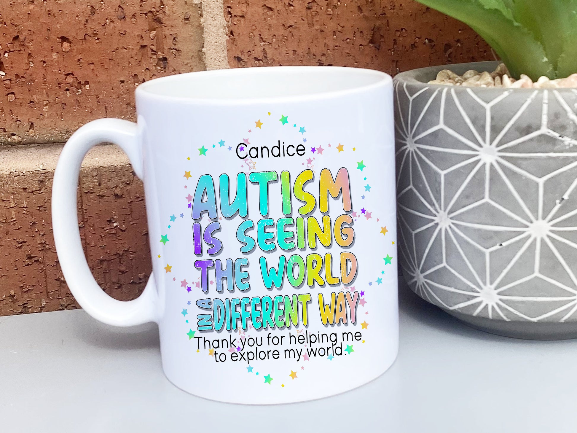 White Ceramic mug. Bright colourful rainbow wording reading Teachers name and Autism is seeing the world in a differnt way, thank you for helping me to explore my world love name