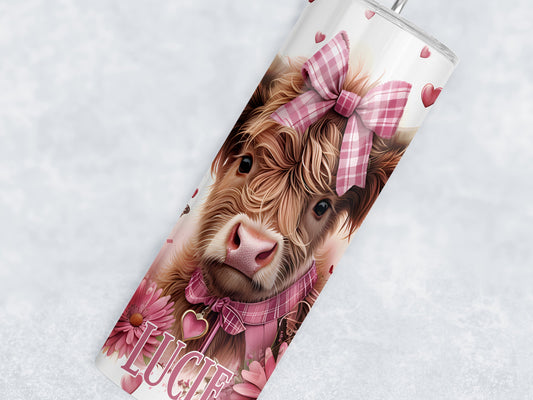 20oz white stainless teel tumbler with a realistic baby highland cow image with pink chequered hairbow and collar, pink flowers and hearts complete the design which wraps around the cup. Matching pink text for name can be added to bottom of tumbler