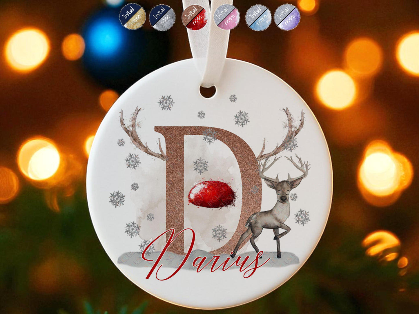 Personalised flat white ceramic Christmas bauble featuring a Christmas reindeer themed design - the letter D balanced on the snowy ground, adorned with antlers, snowflake accents, and custom name example ‘Darius' in festive red script finished off with a proud reindeer standing by the letter – a perfect stocking stuffer, baby’s first Christmas gift, or unique tree decoration."