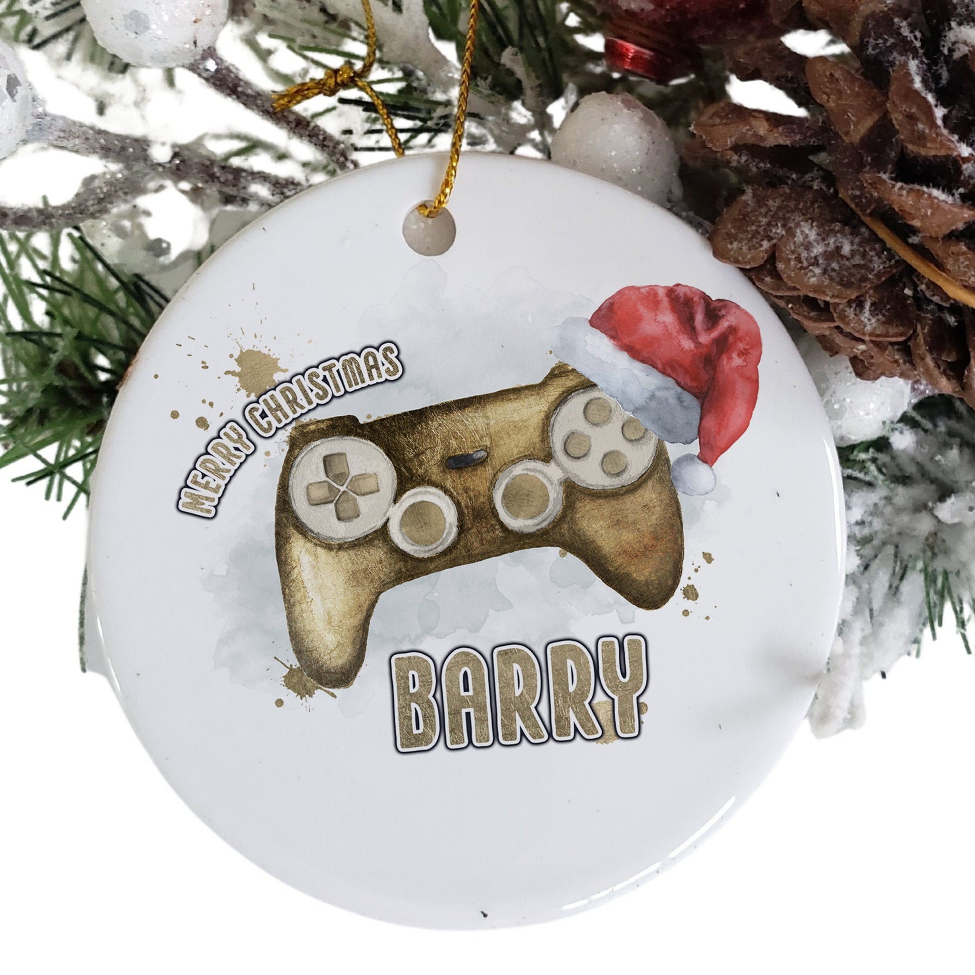White Ceramic personalised Christmas bauble in gift box. Festive Gold coloured gaming Controller with christmas hat and matching gold text in the words Merry Christmas Name.