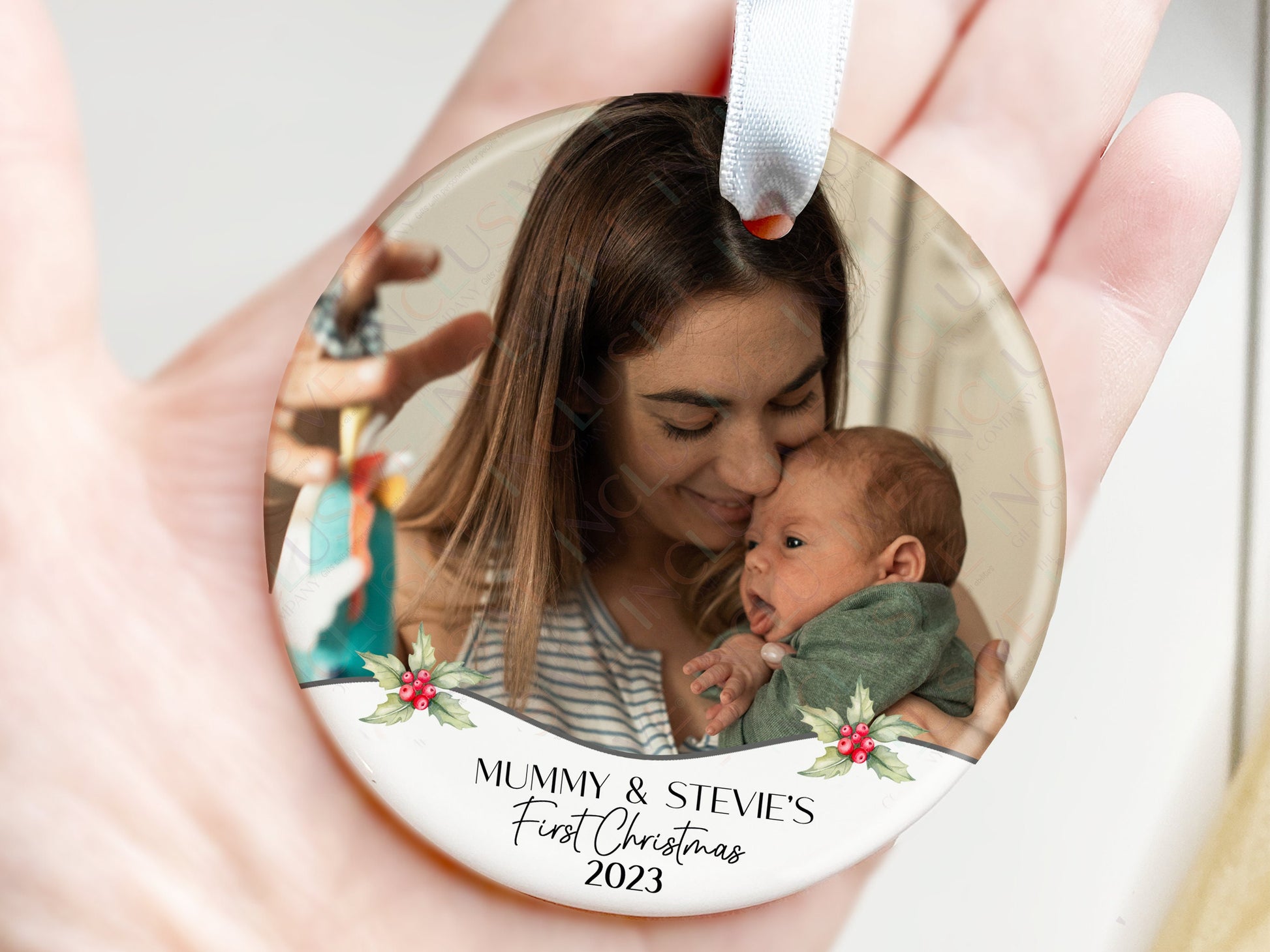 7cm round ceramic bauble with photo of your choice framed with holly and the text Name&#39;s First Christmas 2023 in black. Perfect for baby on their own or photos of baby with mum dad or other family members