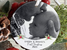 Load image into Gallery viewer, 7cm round ceramic bauble with photo of your choice framed with holly and the text Name&#39;s First Christmas 2023 in black. Perfect for baby on their own or photos of baby with mum dad or other family members
