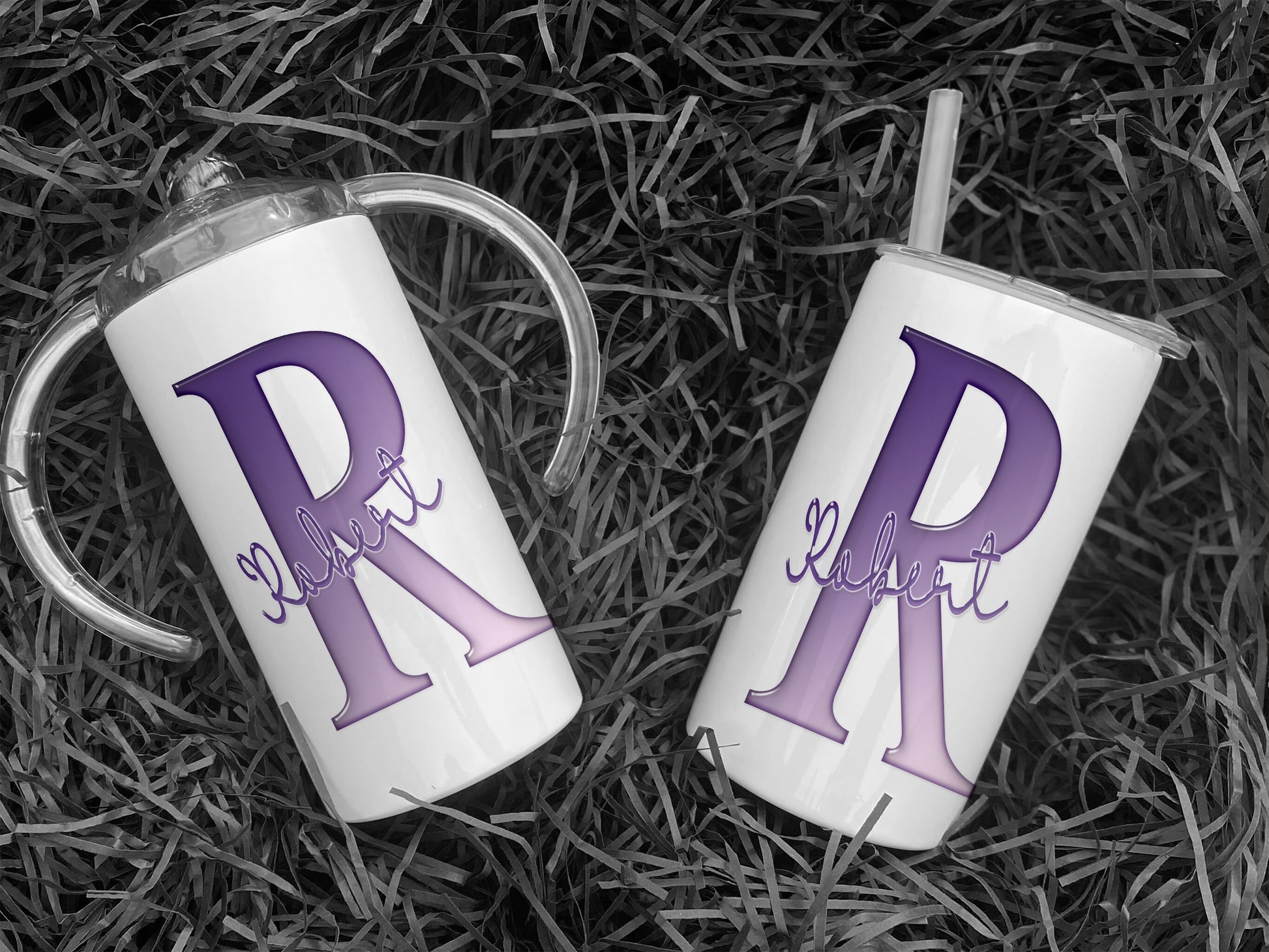 White Stainless steel Sippy cup with clear plastic lid with spout and large handles. A glossy Purple and white Initial with Name in script written across in matching purple.  An additional flat lid with no handles and straw is supplied.