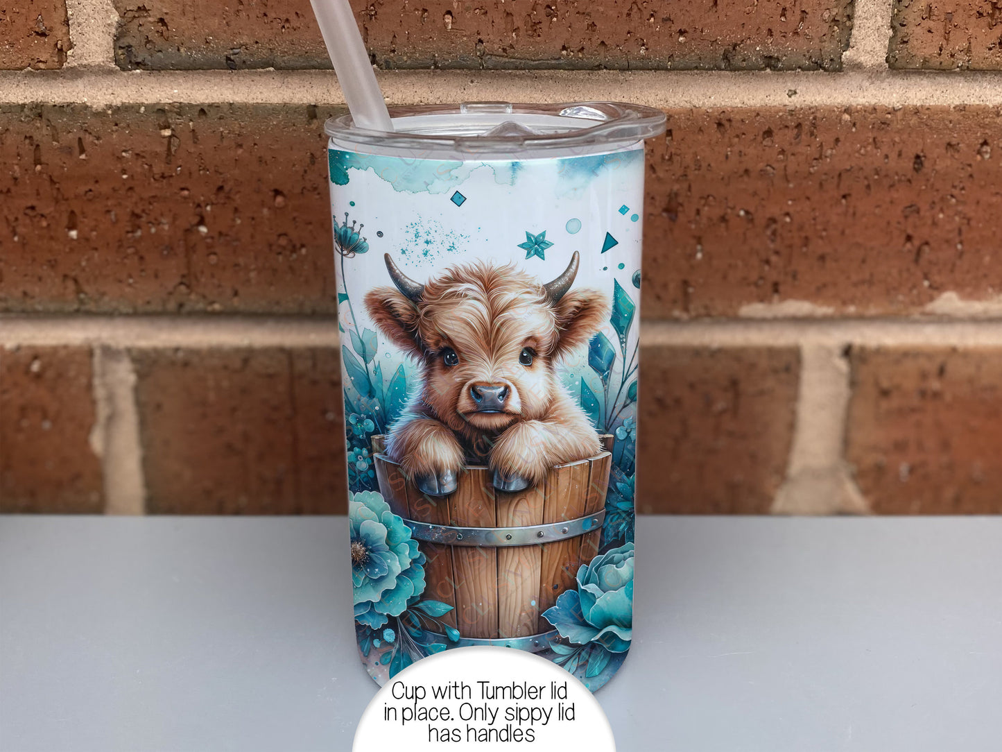 Image shows cup with tumbler and straw lid in place. Only the sippy lid has handlesThis image shows the other design choice of highland cow calf in wooden tub surrounded by blue wild flowers.