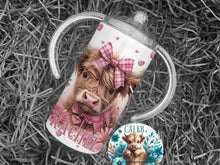 Load image into Gallery viewer, A fluffy highland cow calf with gingham pink and white collar and bow surrounded by pink wild flowers on a white 12 oz sippy cup Also available as highland cow in wooden tub surrounded by blue wild flowers.
